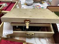 Closed view of the vintage beige jewelry box with subtle flower pattern embossing and gold clasp.