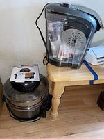 Keurig coffee maker next to Big Boss Rapid Wave oven on wooden table.