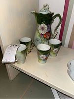 Chocolate set with pot and four cups, all on a shelf, showing the full set.