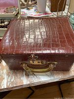 Photo of the vintage travel jewelry case showing brown faux crocodile leather exterior and plastic handle