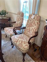 Two matching Ethan Allen upholstered armchairs with floral fabric placed side by side in dining room, showing full view including wooden arms and legs.