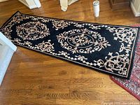 Full view of the runner sized rug on a wooden floor showing overall design and size.