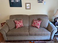Front view of beige Broyhill upholstered sofa, showing four coordinating pillows including two beige and two with red and beige geometric pattern.