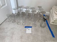 Multiple wine and brandy glasses arranged on carpet with decanter beside