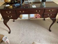 Full front view of Ethan Allen Georgian Court desk showing five drawers with brass pulls and removable glass top.