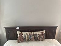 Front view of dark wooden queen headboard with teddy bear pillow placed on mattress.