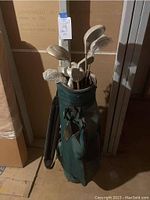 Green Datrek golf bag containing right-handed golf clubs with heads mostly wrapped in plastic.