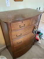 Image showing overall dresser with a visible tiger oak grain pattern, six drawers with brass handles, and curved top edge.