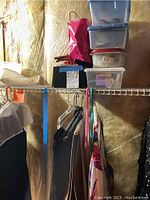 Clothing items including pants and skirt hanging on a rack with plastic storage boxes above