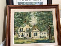 Framed painting of a white house surrounded by trees in a brown wood frame.