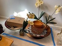 Photo of wooden bowls stacked on a round wooden tray along with glass bowls and faux orchid stems.