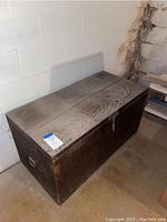 Full wooden trunk with metal side handles, top closed, showing aged wood grain and rustic finish.