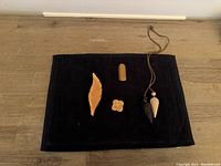 Full view of 2 Bakelite brooches and 2 wood lariat necklaces displayed on black fabric