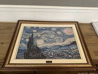 Full frontal view of framed Van Gogh The Starry Night print on wooden surface, showing complete frame and print.