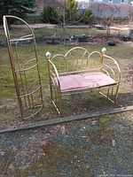 Wide shot of brass bench with pink cushion and matching brass corner shelf outdoors.