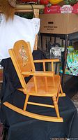 Full side view of vintage child's wooden rocking chair showing armrests, curved rockers, and illustrated backrest.
