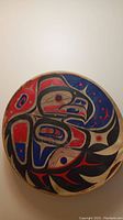 Top view of round 13-inch Indigenous drum showing detailed traditional painted design in red, black, blue, and white.