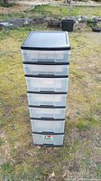 Front view of tall plastic drawer tower showing all seven clear drawers stacked vertically within a black frame.