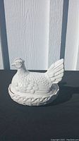 Two white ceramic hen-shaped covered dishes, detailed feathers and base, smooth finish.