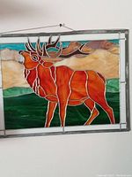 Full view of stained glass moose panel hung on a wall, showing the entire artwork and frame.