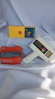 Front view of the red View-Master viewer, yellow View-Master reel packet, and white Fisher-Price Movie Viewer.