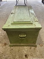 Front view of the antique carpenter's toolbox showing the green paint and metal handle on the side.