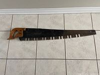 Full view of antique one man crosscut saw showing entire blade and handle from one side
