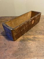 View of the top and inside of the antique wooden drawer showing wear and the split on the inside bottom.