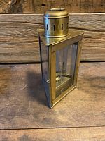 Full frontal view of brass nautical lantern showing glass panels, top vent and hinged access door.