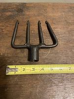 Top view of cast iron trident with a measuring tape showing approximately 6 inches width