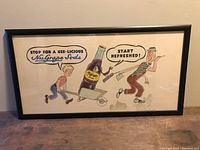 Front view of the framed vintage NU Grape Soda cardboard advertisement showing colorful cartoon figures and bottle under glass in black frame.