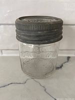 Front view of vintage Crown Mason jar with metal lid on a white surface