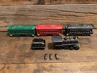 View of the full train set on a wooden surface showing locomotive, tender, passenger cars, and connecting hooks.