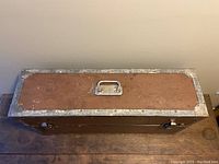 Top view of the vintage carpenter's suitcase box showing the handle centered on the lid and metal corner reinforcements.