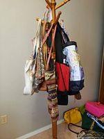 Photo showing assorted bags hanging on a wooden stand including white, multicolored, and patterned bags
