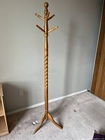 Full view of the wooden coat tree showing its height and twisted center pole.