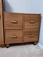 Front view of wood dresser showing four drawers with curved handles and wood grain finish.