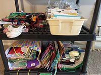 Two shelves of assorted gift bags with handles in various colors and patterns, and a beige plastic bin filled with greeting cards and envelopes.
