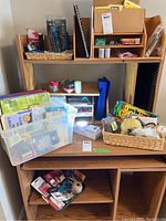Overview of the office supply items displayed on wooden shelving units and in plastic containers, showing a variety of stationery items, tapes, and lighting.
