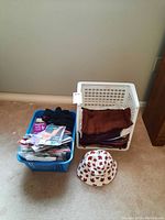 Overview of lot with two baskets; one contains packaged pantyhose, the other holds folded scarves; a white hat with red maple leaf print placed in front