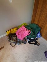 Photo showing six tote bags in various colors and styles arranged on the floor against a wall
