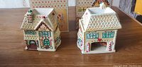 Both ceramic gingerbread houses side by side, showing painted details and shape.