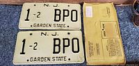 Front sides of two vintage New Jersey license plates with number 1-2 BPO and envelope beside them