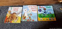 Front covers of the three large hardcover children's books: 'If You Give a Moose a Muffin', 'If You Give a Dog a Donut', and 'Pete the Cat: The Bike Lesson Storybook Set'.