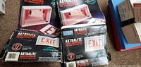 Two boxed Astralite 2000 universal exit sign retrofit packages shown on a floor surface.