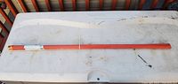 Six red markers lying horizontally on a table, showing full length and reflective tape on one end.