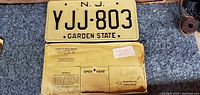 Photo showing front view of vintage New Jersey license plate YJJ-803 and accompanying DMV envelope