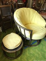 Bamboo swivel barrel chair with yellow cushioned seat and matching round bamboo ottoman with yellow cushion, set on green carpet surrounded by other furniture.