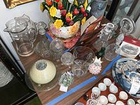 Overall assortment including glass pitchers, decanters, floral vase, wooden fish, footed platter, and decorative beads