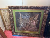 Frontal photo of a framed oriental art piece with traditional figures on elephants and an ornate wooden frame with green border.